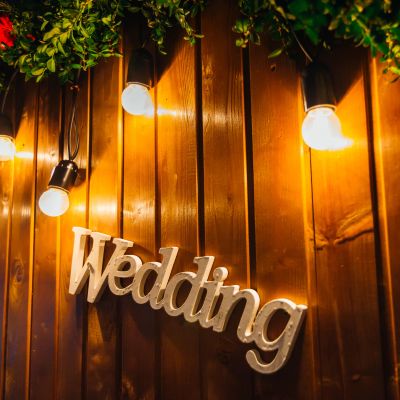 Warm string lights on wood paneling with a welcoming sign.