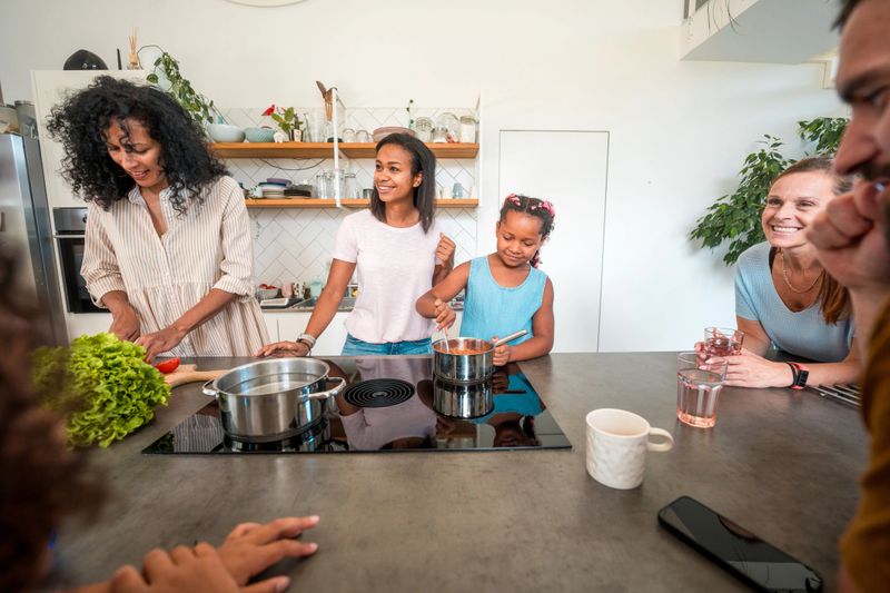 Diverse family share their joy as they cook, chat, and support each other during meal preparation.