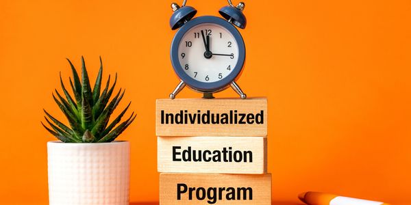 Clock atop blocks labeled 'Individualized Education Program' beside a potted plant.
