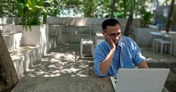 Brightly colored parrots perched on a branch in a lush forest.