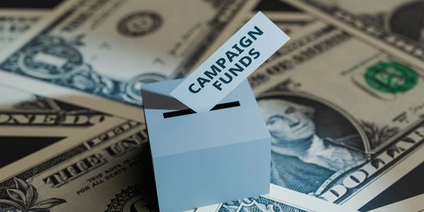 A paper box labeled 'CAMPAIGN FUNDS' on dollar bills.