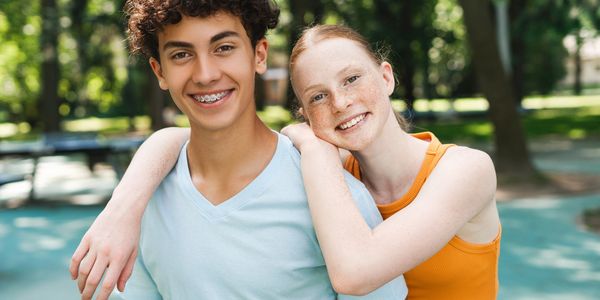 Two happy teenagers smiling outdoors, showing friendship and warmth.