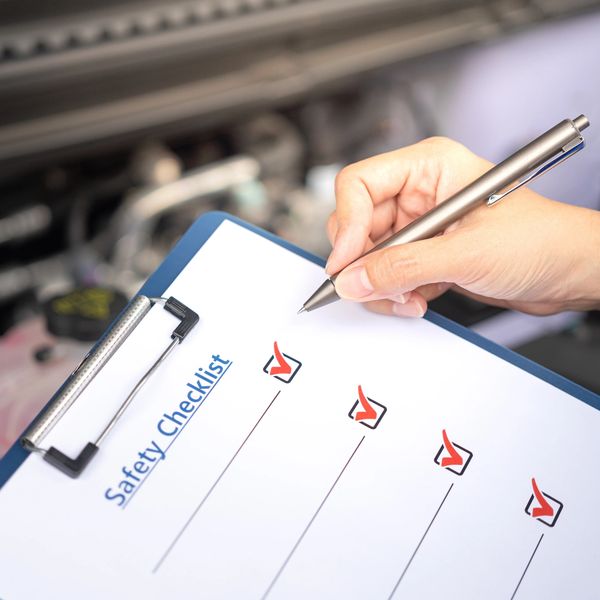 Person marking all items on a safety checklist with red checkmarks.