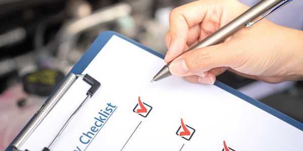 Person holding pen with a safety checklist on a clipboard, several items checked off.