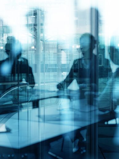 A group of people sitting at tables in front of windows.