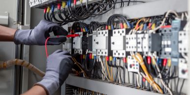 Electrician working on wiring inside a building under construction.