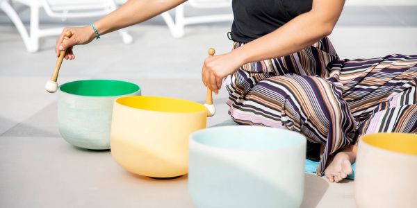 Person playing colorful singing bowls with mallets.