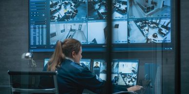 Security professional monitoring multiple surveillance screens.