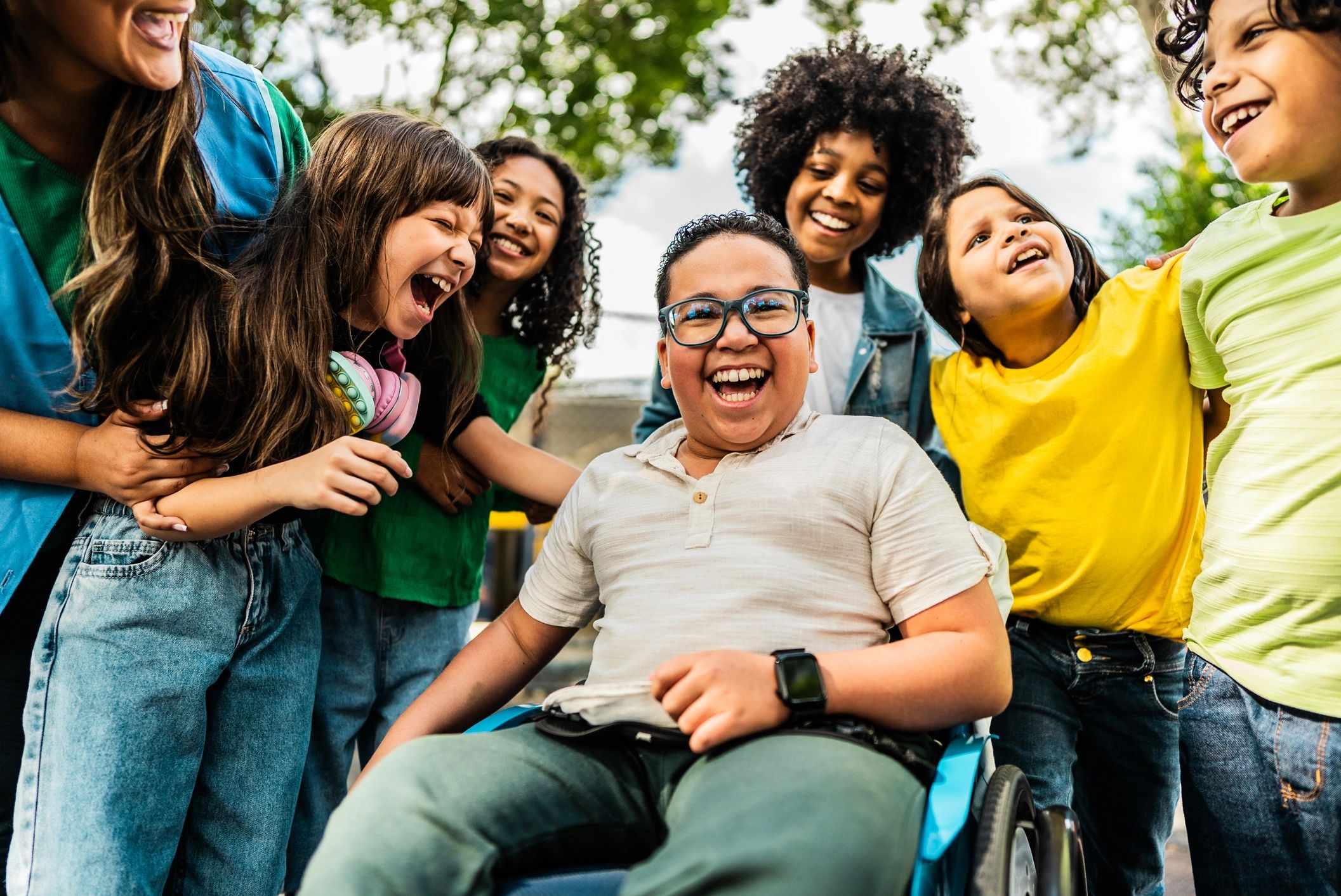 Group of happy children including a boy in a wheelchair.