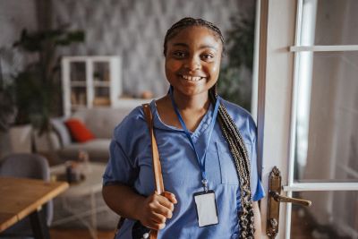 Smiling woman with braided hair wearing a blue shirt and ID badge.