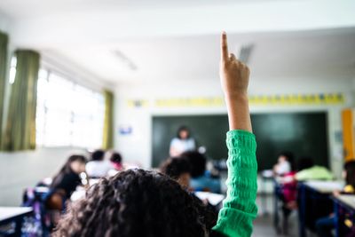 Student raising hand in classroom to answer a question.