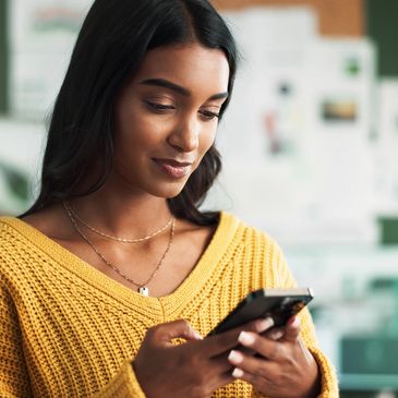 Young woman in a yellow sweater using her smartphone.