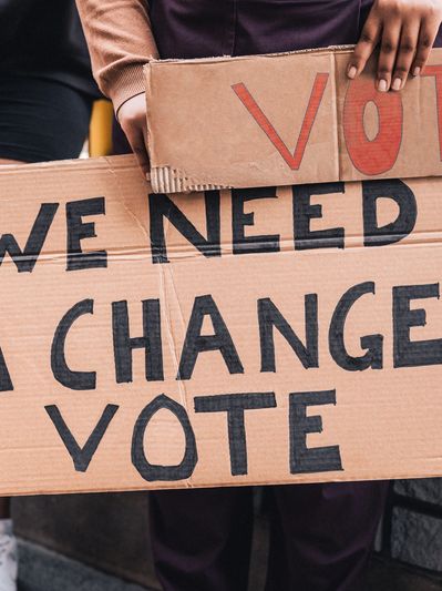 People holding cardboard signs advocating for change with the word 'VOTE'.