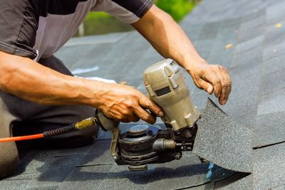 A person holding roofing nailer