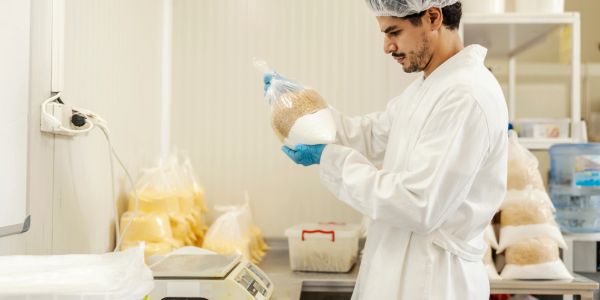Gıda laboratuvarında paketlenmiş ürünü inceleyen adam.