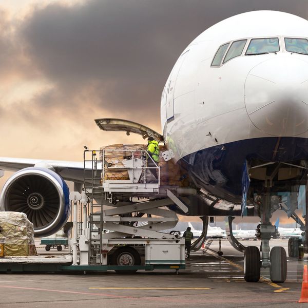 Cargo being loaded into a large airplane at the airport during sunset.