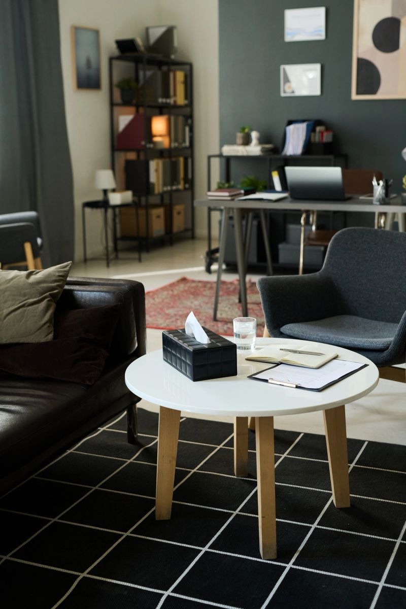 Modern office setting featuring a comfortable black chair and wooden furniture near bookshelves and decor items enhancing a clean and tidy environment with natural aesthetics