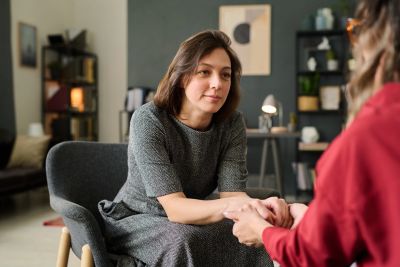 A woman comforting another by holding her hands during a conversation.