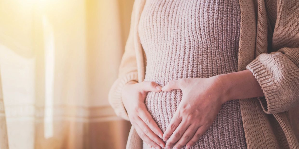 Expectant mother making heart on belly before prenatal massage at Wholly Spirit Hands Sugar Land.