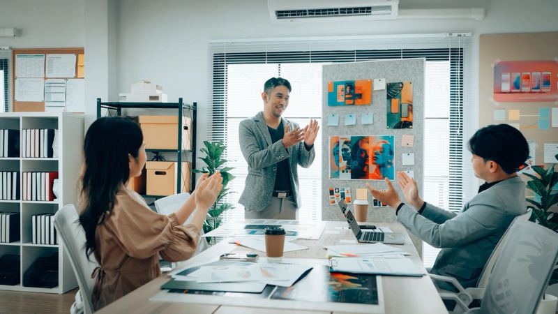 Creative team applauding and celebrating after a successful mobile app design presentation in a modern office. Positive collaboration and teamwork highlighted.