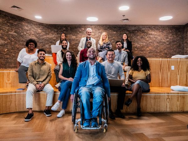 Diverse group of smiling people posing in a modern wooden and brick room.