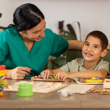 Therapist helping a smiling boy with educational toys.