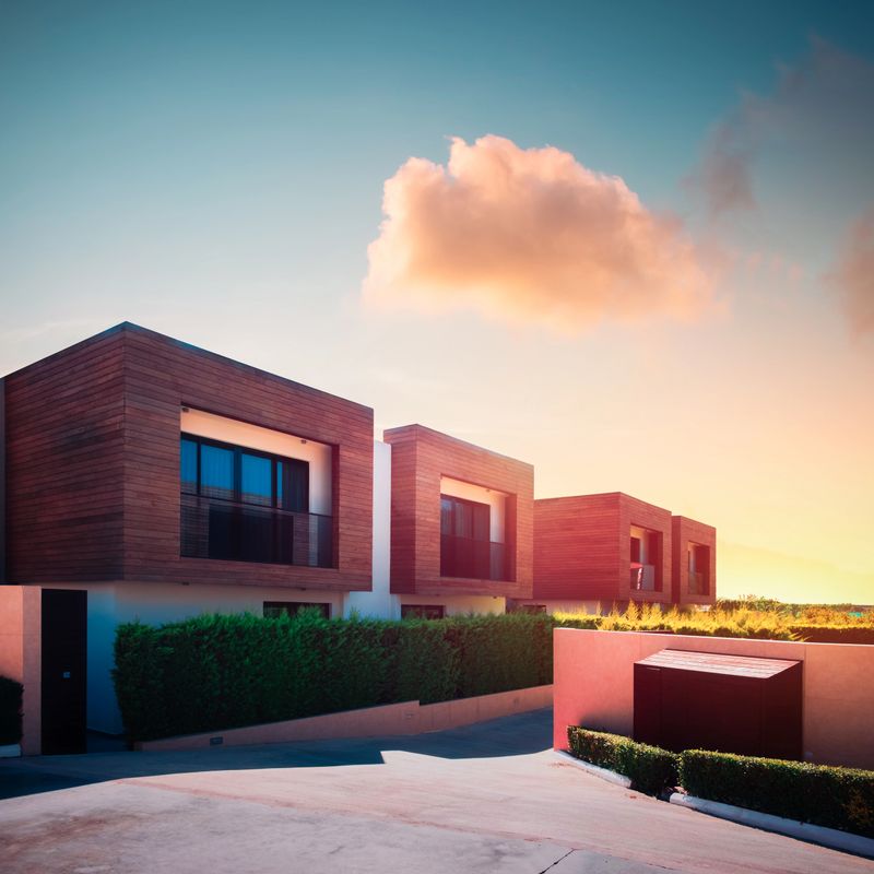 Modern houses with green plant wall and pink cloud in sunrise sky on background. Actual eco architecture