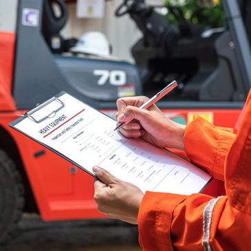 Worker conducting a safety inspection on a forklift with a checklist.