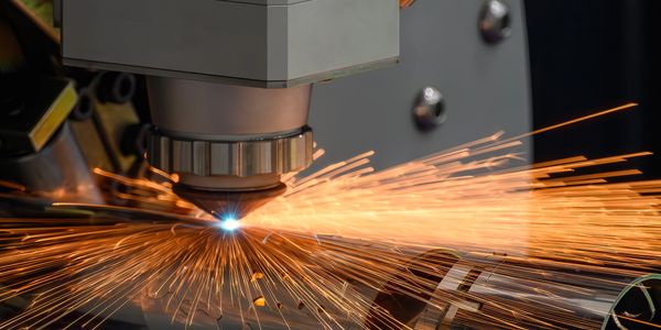 Laser cutting machine producing bright sparks on metal.