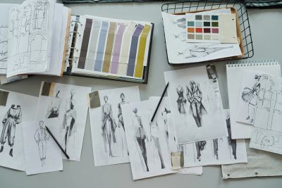 Fashion sketches and color swatches spread on a designer's workspace.