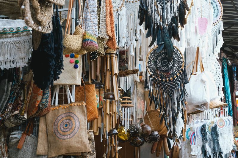 A close-up view of colorful handmade crafts and textiles displayed in a market. The intricate designs and vibrant colors reflect the local craftsmanship and cultural heritage, showcasing a variety of unique items.