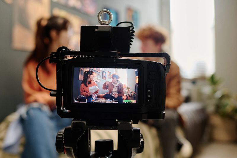 Two people sitting and engaging in conversation while professional camera capturing their interaction Camera screen displaying a clear view of the ongoing scene