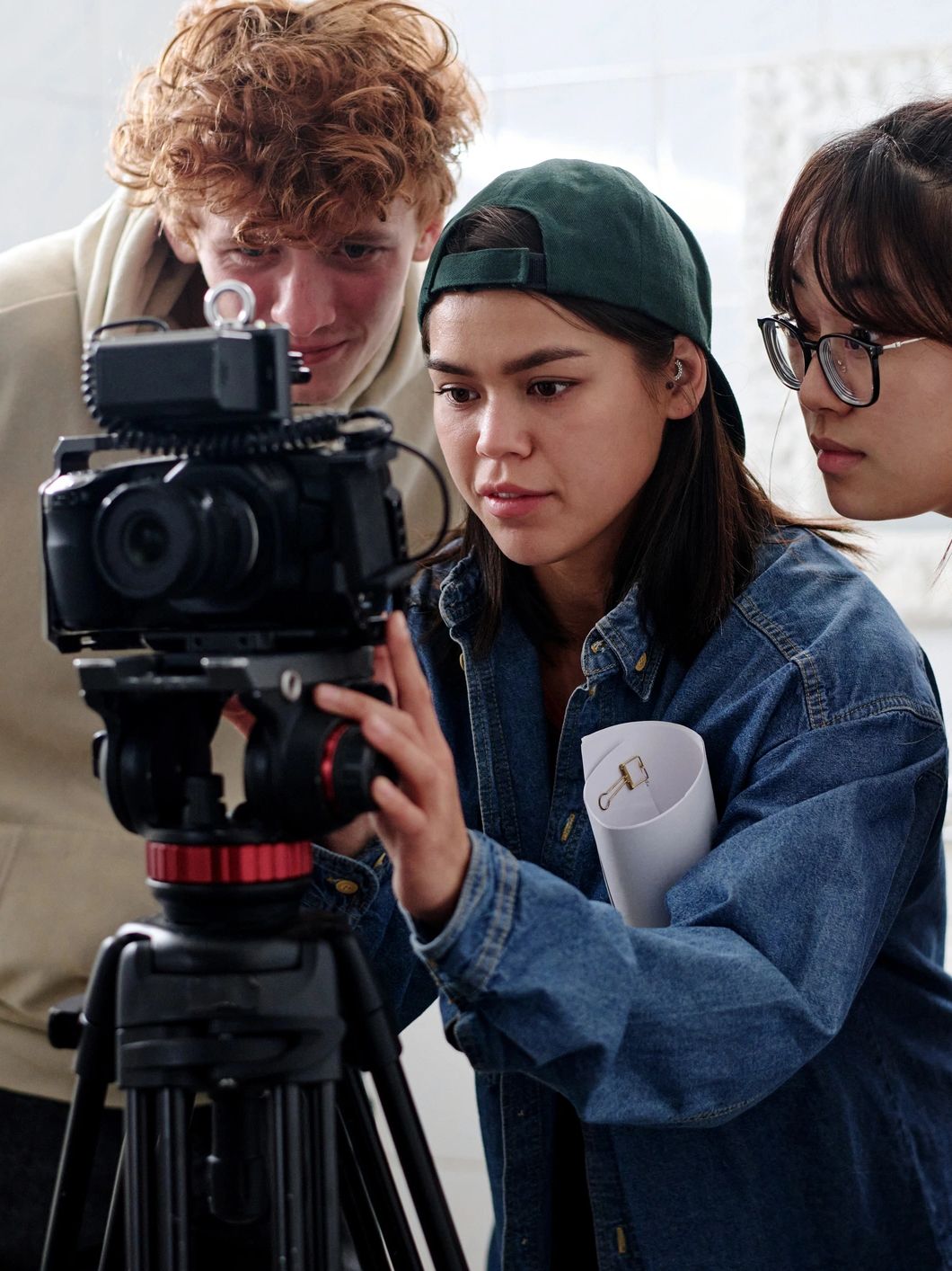 Three young filmmakers reviewing footage on a camera.