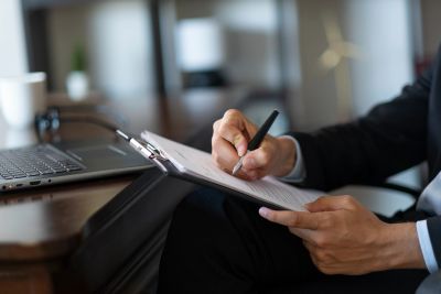 Person writing on a clipboard in an office.