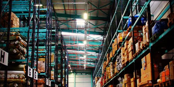 Spacious warehouse aisle with tall shelves stocked with boxes and goods.