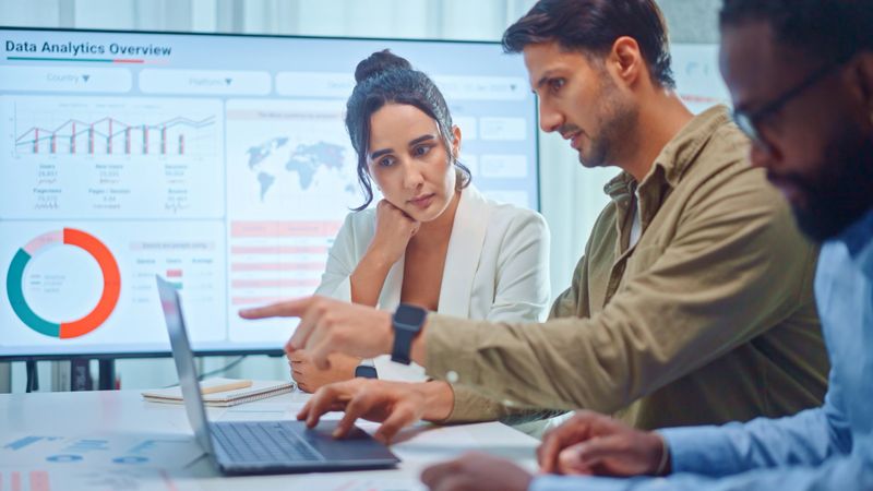 A team of multiethnic developers is meeting to discuss the data analytics of marketing.