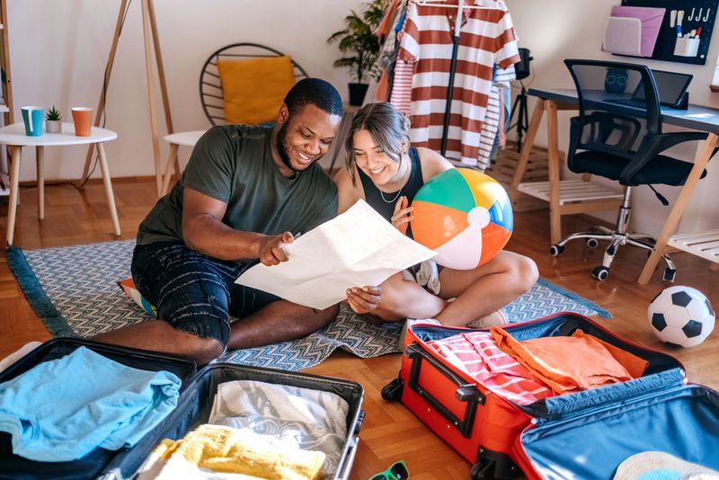 People enjoying with packing suitcases together before leaving on vacation searching for travel destination using paper map
