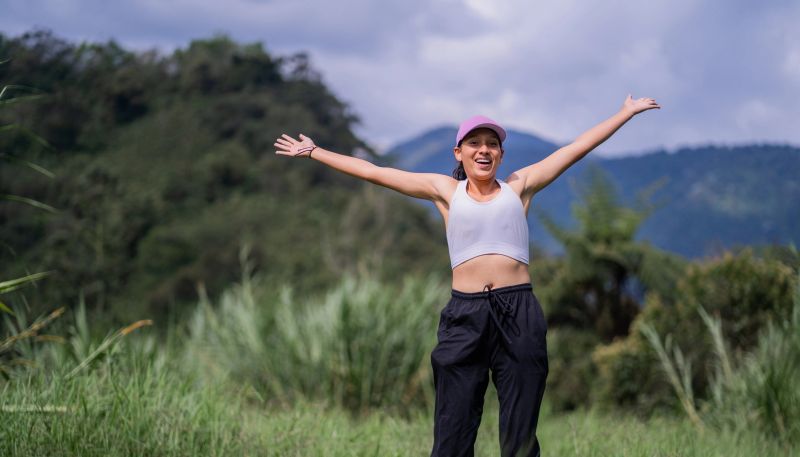 young hispanic latina woman smiling happily and jumping into the open air with open arms