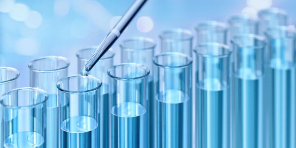 Pipette dropping liquid into test tubes in a lab.