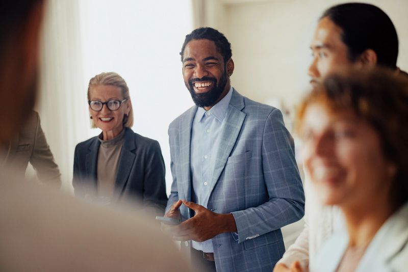 Team of diverse professionals smiling and interacting in a modern office setting. Shows collaboration, teamwork, and a positive business environment.