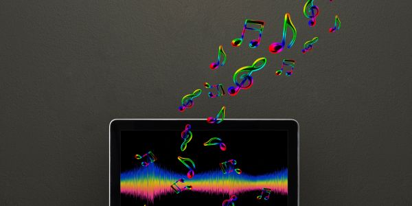 Colorful musical notes rising from a laptop screen with sound waves.