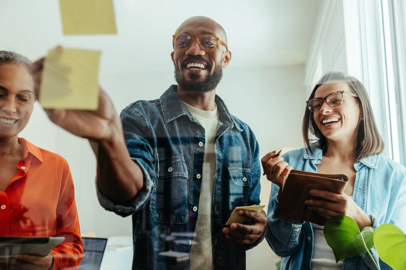 Diverse group of professionals in a business workshop brainstorming and sharing ideas while taking notes and collaborating.