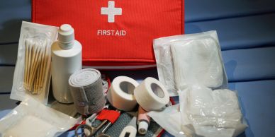 First aid kit with medical supplies on a blue surface.