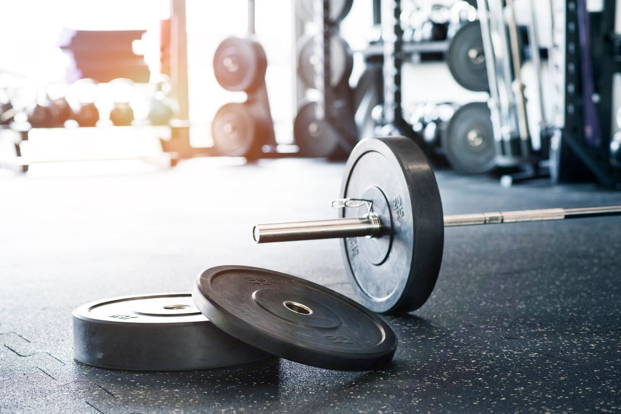 Rows of metal barbells on floor and rack for strength training in the gym.