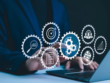 Person interacting with digital gears icons on a laptop, symbolizing business and technology.