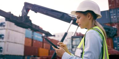 Woman engineer at shipping port using a tablet.