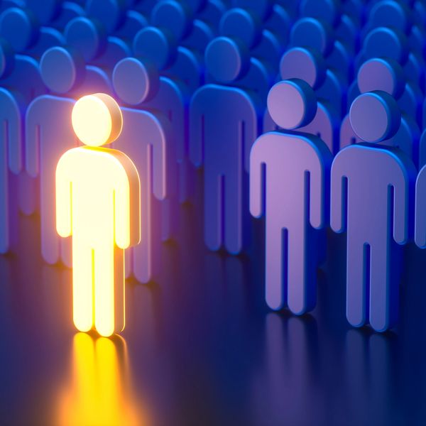 A glowing figure stands out among a crowd of blue figures, symbolizing uniqueness.