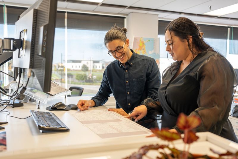 Two middle aged architectural colleagues reviewing drawings and design details in a modern office for and upcoming project