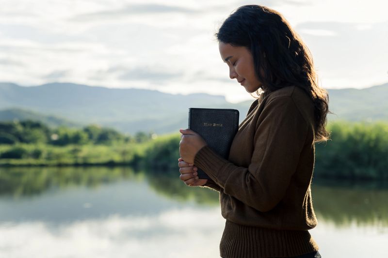 Young woman praying to god with the bible, Christianity, Concept of faith for god and teachings from the Bible.
