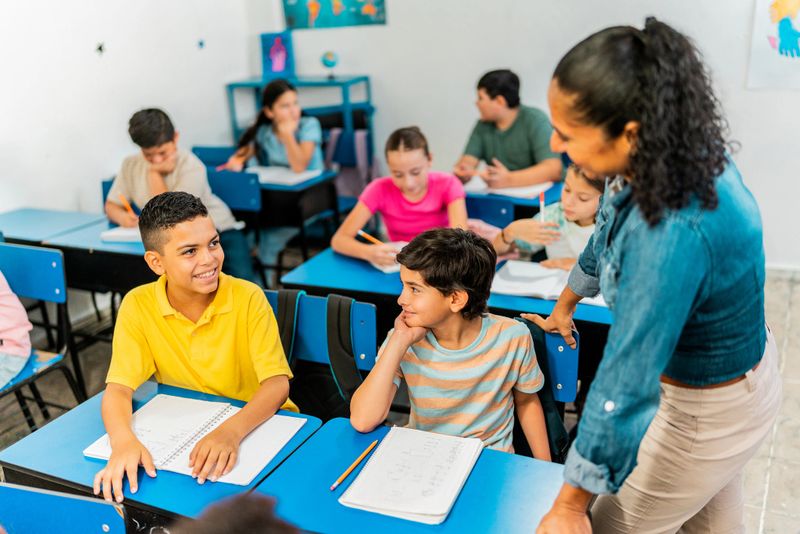 Child boys talking to teacher during class at school